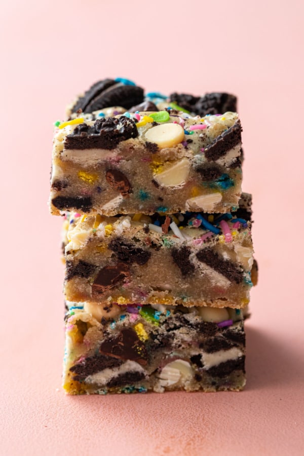 Stack of three sprinkle party blondies on a pale pink background