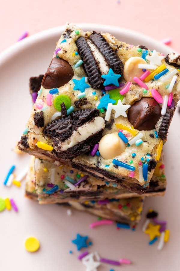 Closeup, top of a stack of square-cut sprinkle party blondies showing the various mix-ins baked on top