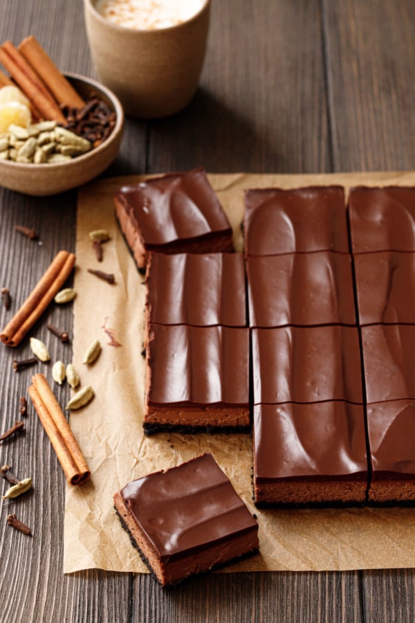 Chocolate Chai Cheesecake Bars cut into squares, on natural parchment and a wood background