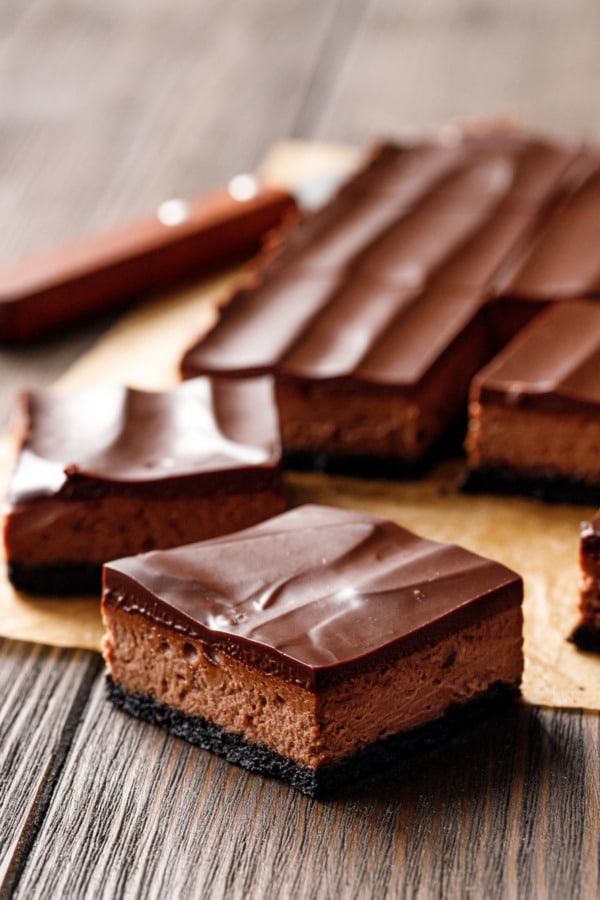 Closeup, Chocolate Chai Cheesecake cut into square, on natural parchment and wood background