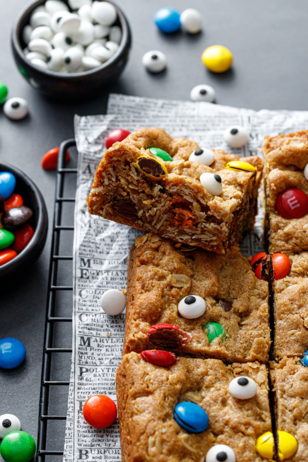 Cut square of Monster Cookie Bar, tilted to show the texture of the oats and candy pieces inside.