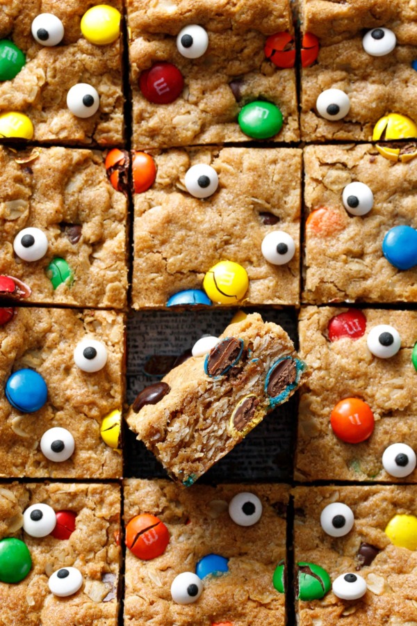 Square grid of cut Monster Cookie Bars, one tilted on its side to show cross-section