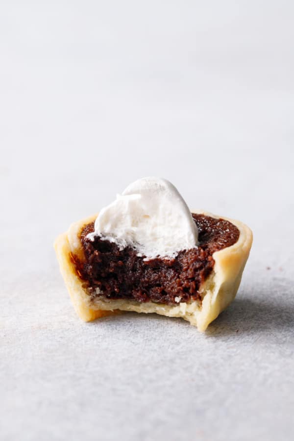 Closeup of one Mini Bourbon Fudge Pies with a bite taken out of it to show the fudgy texture.