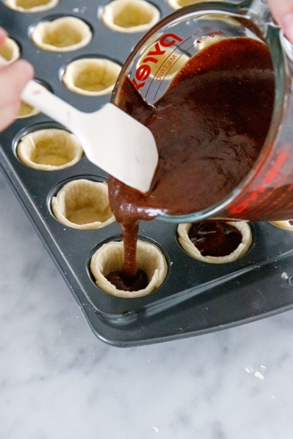 Pouring the chocolate fudge filling into the par-baked mini crusts