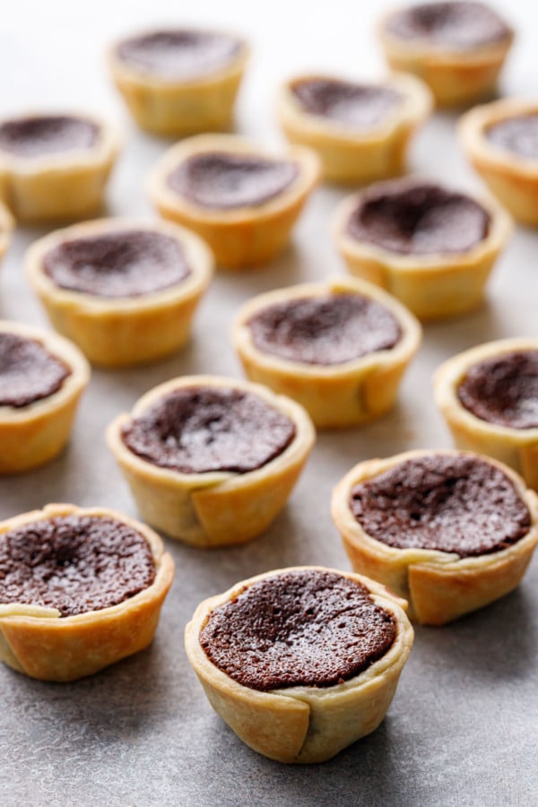 Rows of Mini Bourbon Fudge Pies, shallow depth of field on a gray background