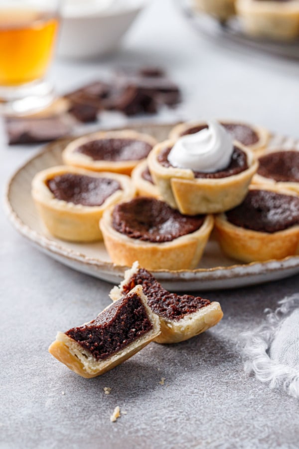 Plate of Mini Bourbon Fudge Pies, one cut in half in the foreground to show texture