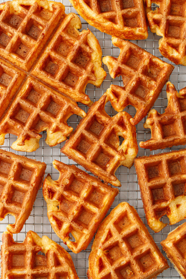 Randomly arranged quarter rounds of Savory Cheddar Cheese Waffles on a wire rack