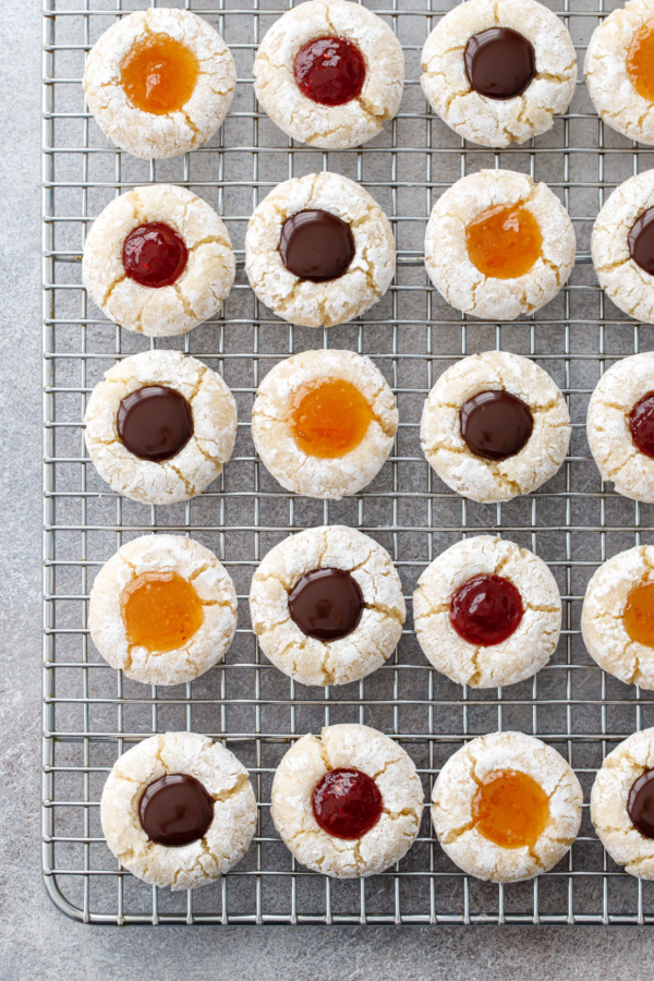 Rows of Amaretti Thumbprint Cookies in neat rows on a wire rack, alternating between three kinds of filling.