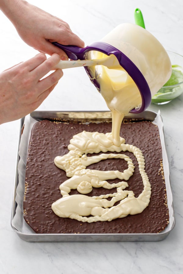 Pouring melted white chocolate on top of set chocolate layer