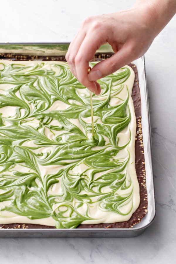 Using a toothpick or skewer to swirl the two colors of white chocolate into pleasing swirls