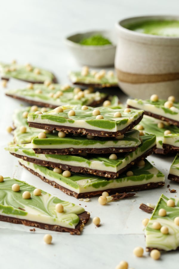 Stack of cut pieces of Matcha White Chocolate Crunch Bark, showing the multiple layers and the crunchy bits in the dark chocolate layer.