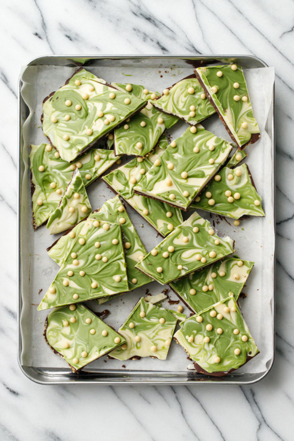 Overhead, sheet pan with random uneven cut pieces of Matcha White Chocolate Crunch Bark