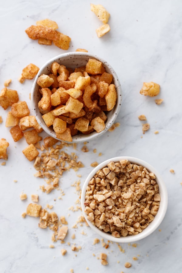 Small bowls with cookie mix-ins messily scattered around: cinnamon dried apples and toffee bits.