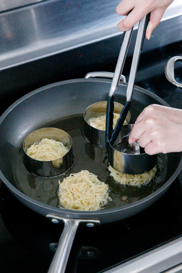 Lifting the ring molds to reveal the perfectly shaped latke