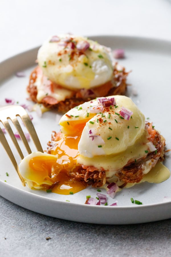 Latke Eggs Benedict with a piece cut out to show the perfectly jammy egg yolk