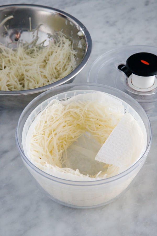 Spinning shredded potato in a paper-towel lined salad spinner to remove excess liquid.