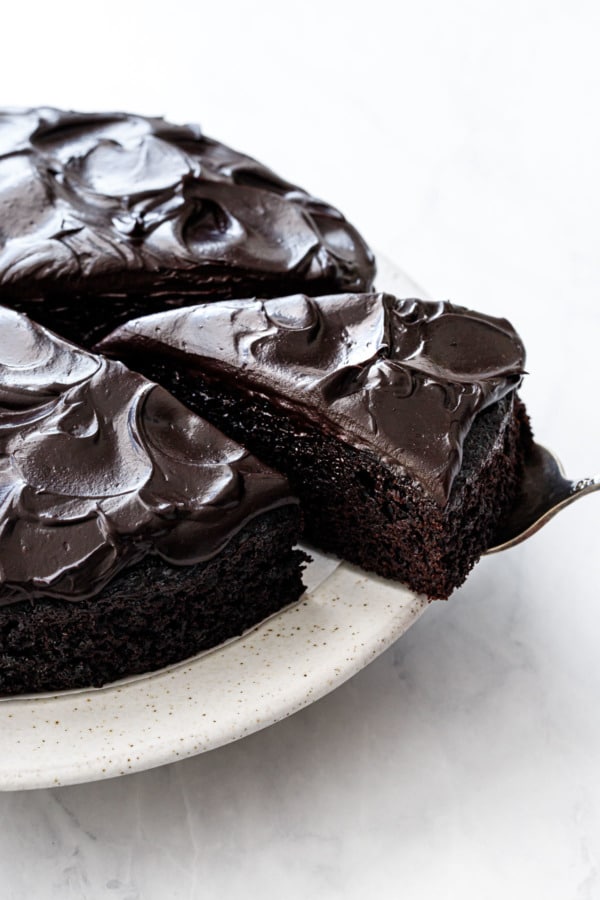 One triangular slice cut from a Sour Cream Chocolate Cake, with swirls of glossy chocolate frosting