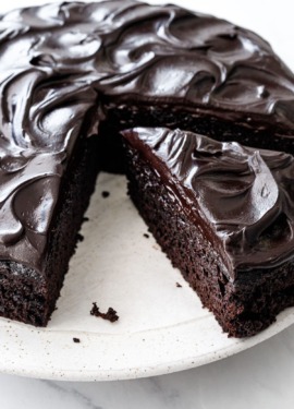 One triangular slice cut from a Sour Cream Chocolate Cake, with swirls of glossy chocolate frosting