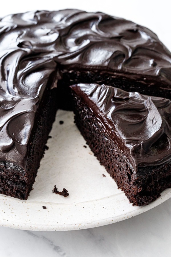 One triangular slice cut from a Sour Cream Chocolate Cake, with swirls of glossy chocolate frosting