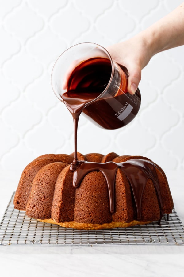 Almond Bundt Cake sitting on a wire rack, being drizzled with Amaretto Ganache and dripping down the sides