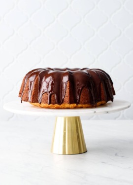 Almond Bundt Cake with Amaretto Ganache on a gold and marble cake stand with tile background
