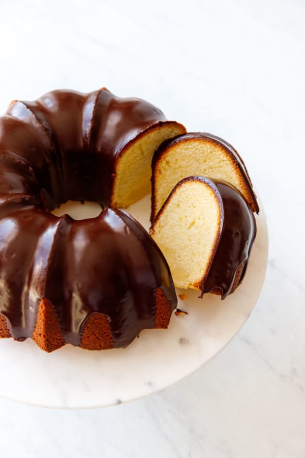 Cut slices of Almond Bundt Cake with Amaretto Ganache, slightly tilted to show the interior cake texture, on a marble cake stand