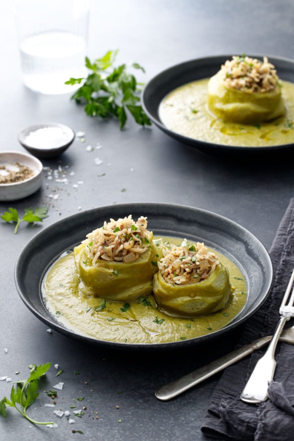 Dark gray bowls with Hungarian Stuffed Kohlrabi (one bigger and one smaller bulb) surrounded by a green kohlrabi green puree