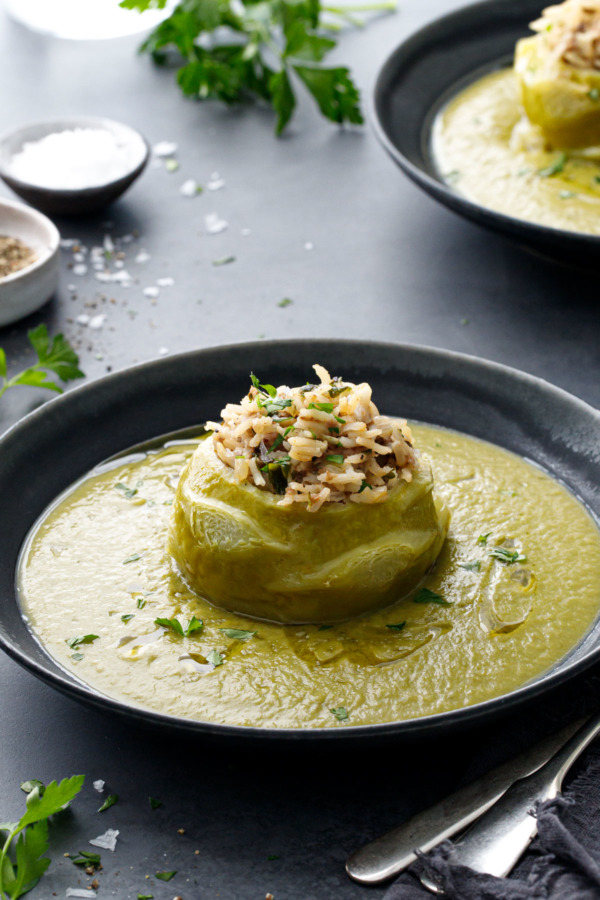 Hungarian Stuffed Kohlrabi in a dark gray bowl, surrounded by a green kohlrabi puree