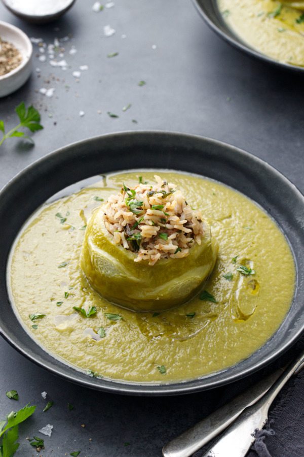 Hungarian Stuffed Kohlrabi in a dark gray bowl, surrounded by a green kohlrabi puree