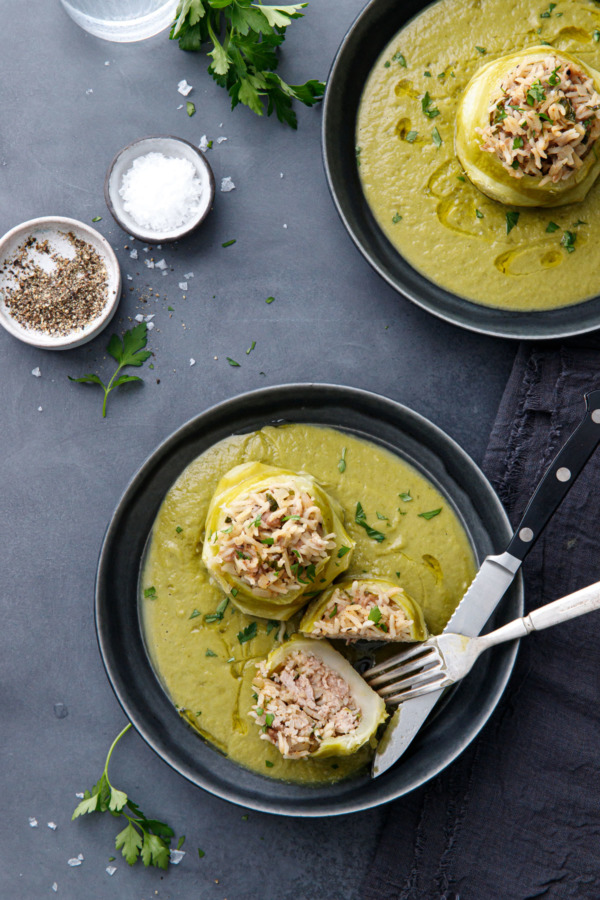 Overhead, two bowls of Hungarian Stuffed Kohlrabi, with one bulb cut in half to show the pork and rice filling inside