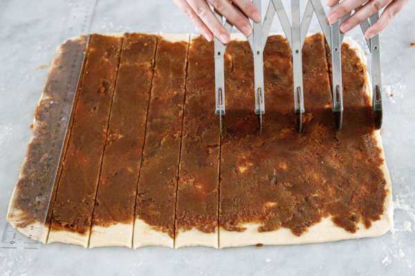 Using a multi-blade pastry cutter to cut even strips out of dough.