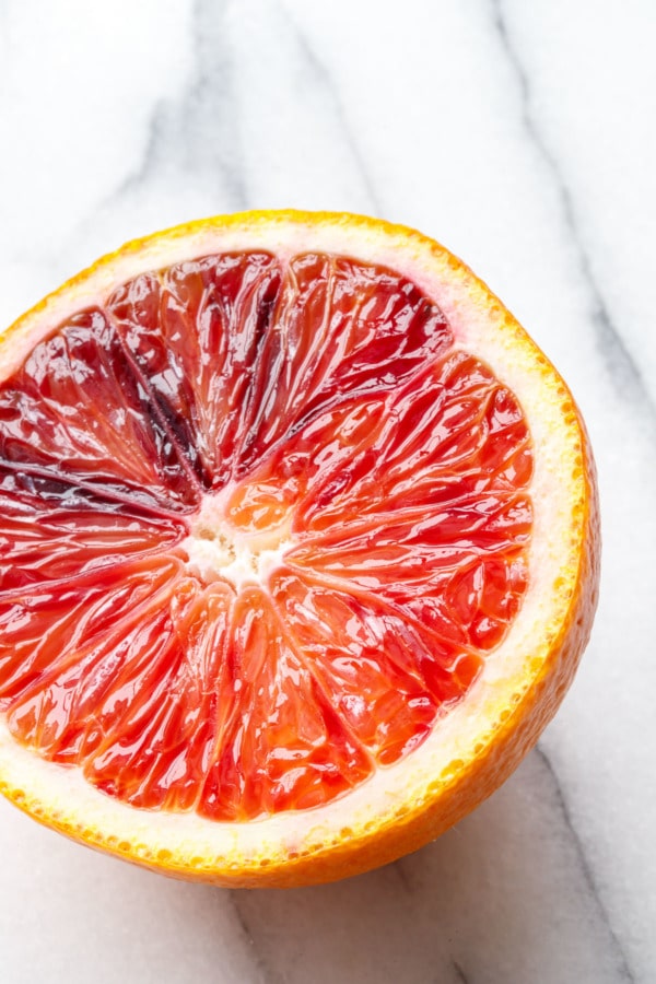 Closeup macro shot of a cut half of a blood orange, with a vibrant gradient of color from orange to red.