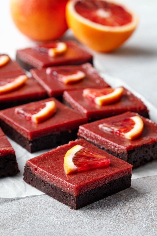 Cut squares of Blood Orange Curd Brownies showing the perfectly defined layers of dark chocolate brownie and vibrant red blood orange curd.