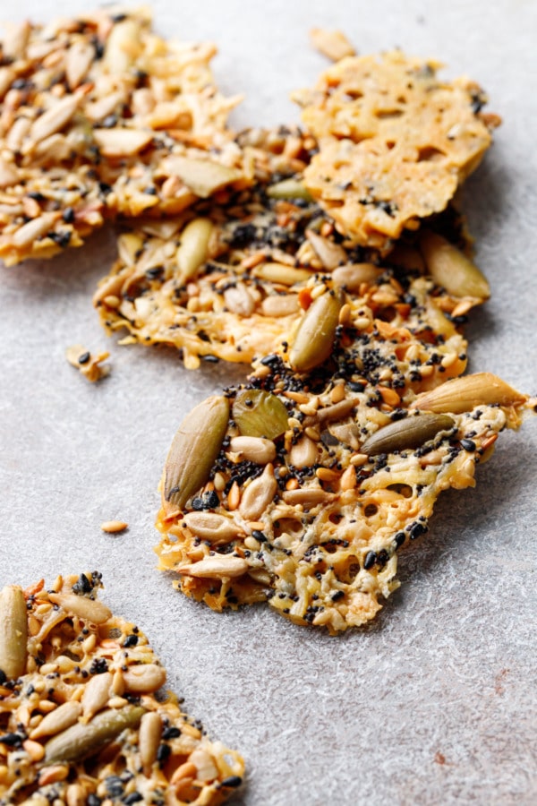 Messy scattered pieces of Seeds and Cheese Crackers, broken up on a gray background