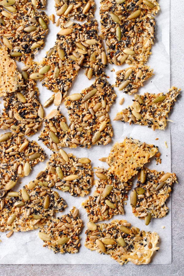 Overhead roughly broken pieces of Seeds and Cheese Crackers on a piece of parchment