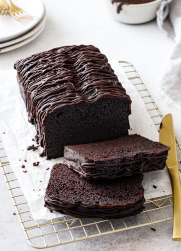 Sliced Chocolate Olive Oil Loaf Cake with drizzle of chocolate glaze on a wire baking rack