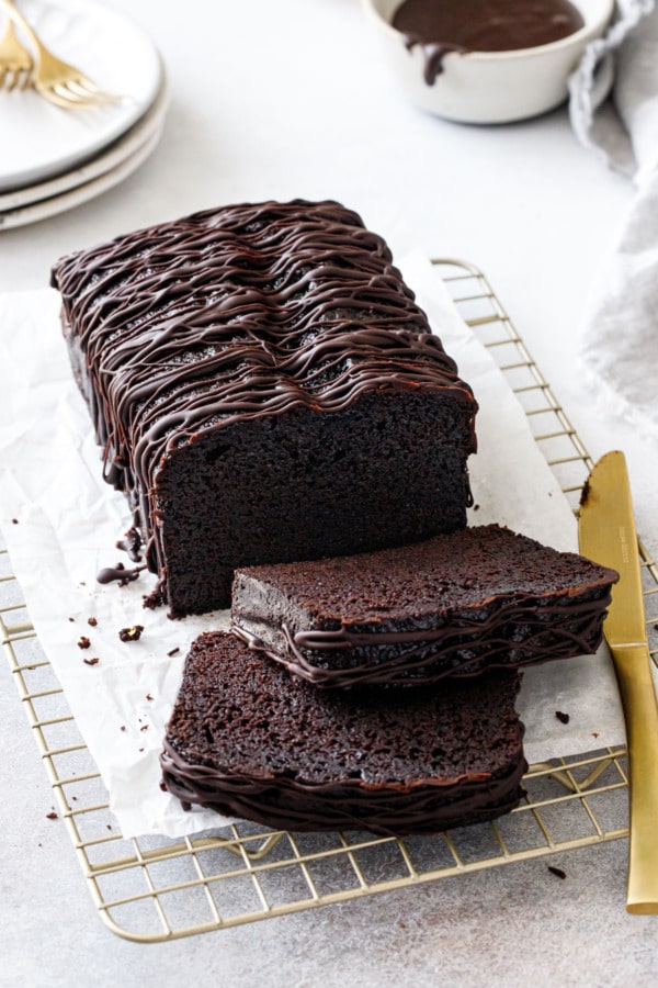 Sliced Chocolate Olive Oil Loaf Cake with drizzle of chocolate glaze on a wire baking rack