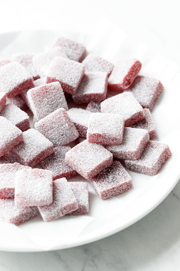 White plate with pile of Homemade Sour Strawberry Gummies after rolling in sour sugar