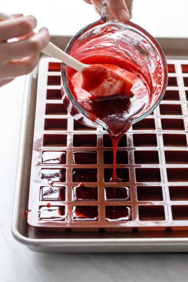 Pouring the liquid gummy candy into square silicone molds.