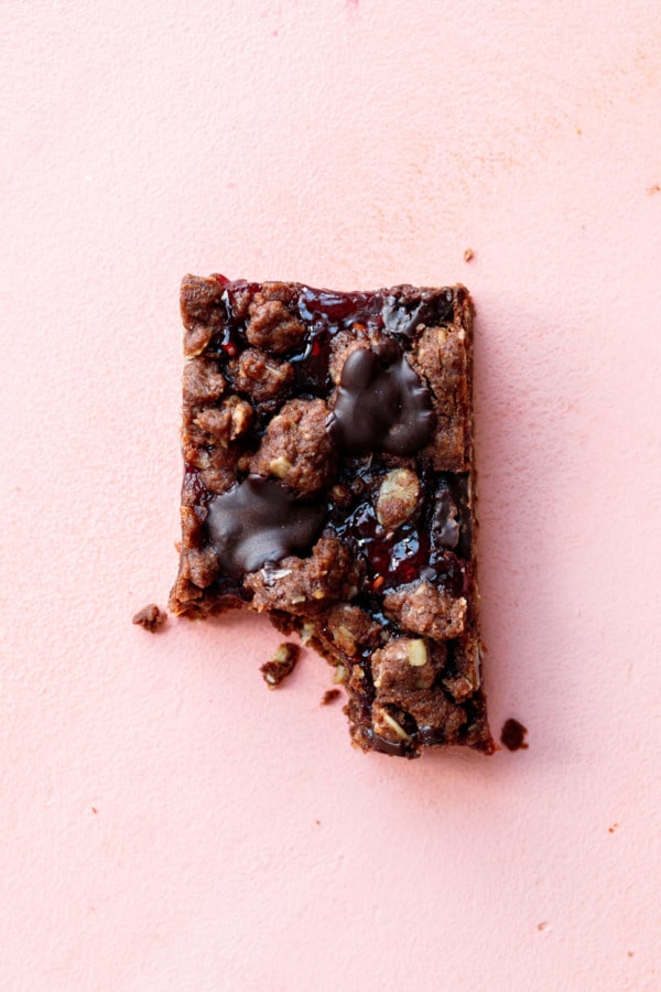 Overhead, one Chocolate Raspberry Crumb Bars with a bite taken out of it and scattered crumbs.