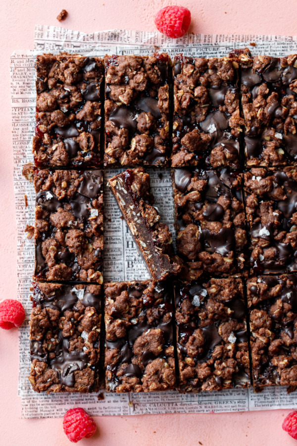Overhead, Chocolate Raspberry Crumb Bars cut into rectangles, one propped on its side to show the layers.