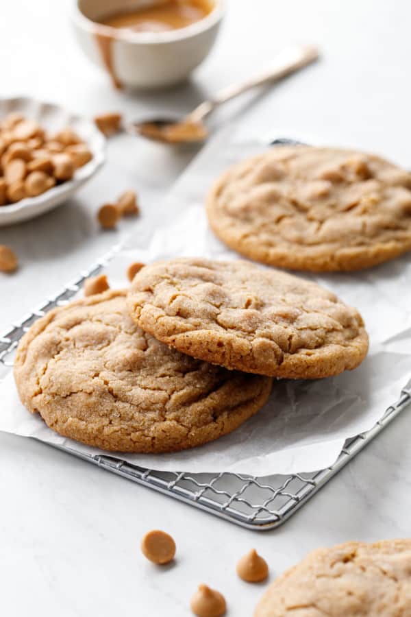 Crackly peanut butter chip cookies on a wire rack and wrinkled parchment.
