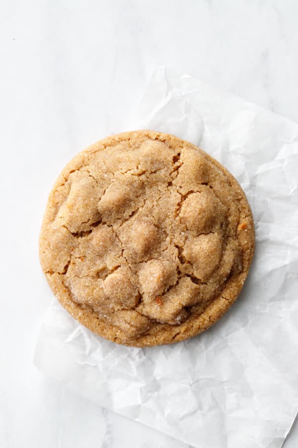 Close up, perfectly round Salted Peanut Butter Chip Cookie on a crinkled piece of parchment.