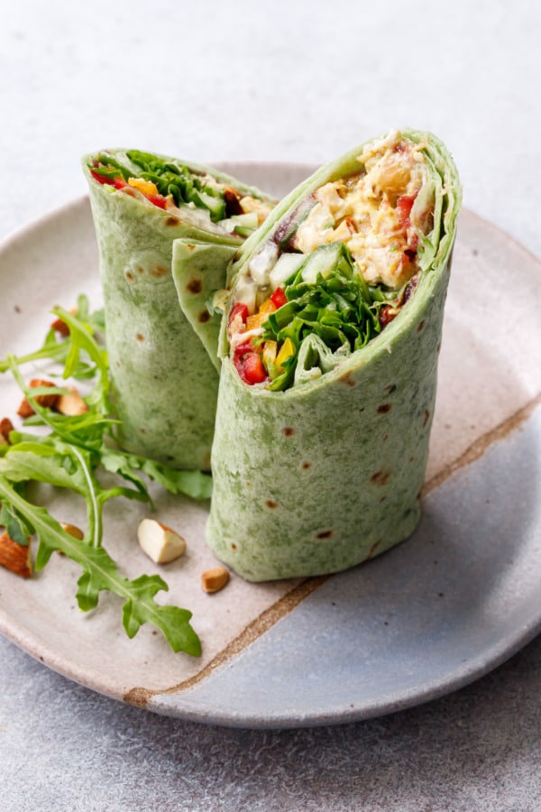 Curried Chicken, Chickpea & Arugula Wraps cut in half diagonally to show a cross section of the fillings.