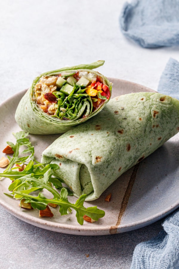 Curried Chicken, Chickpea & Arugula Wraps cut in half diagonally to show a cross section of the fillings.