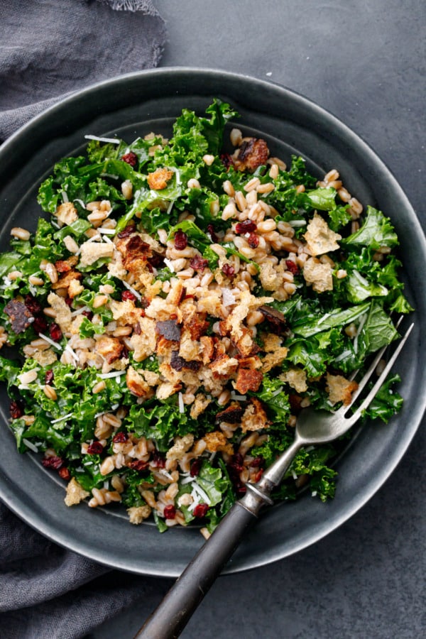 Overhead, closeup of bowl of Kale & Farro Salad with Sourdough Breadcrumbs with vintage fork.