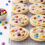 Wire rack with rows of M&M Sugar Cookies, scattered multi-colored M&Ms candies scattered around.