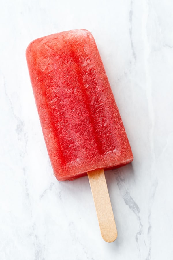 Single Tequila Watermelon Popsicles closeup showing ice crystals and gorgeous red color.