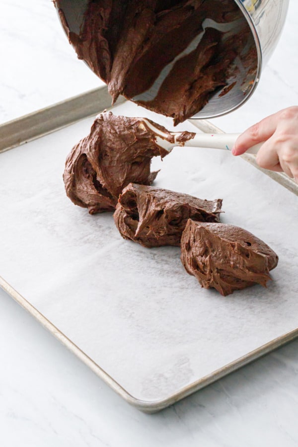 How to make brownie ice cream sandwiches: pour brownie batter into a parchment-lined half sheet pan.