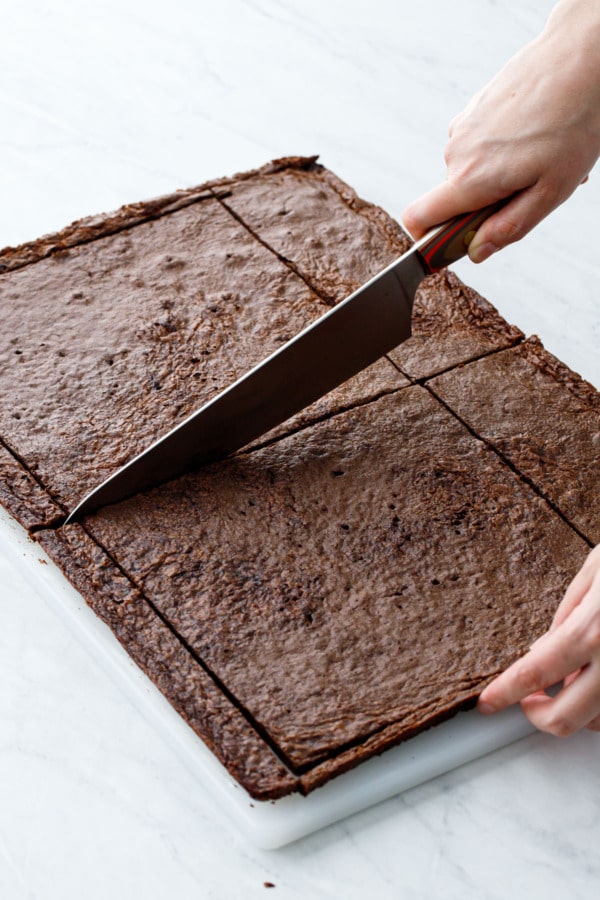 How to make brownie ice cream sandwiches: Cut brownie into even 8-inch squares, cutting all the way through the parchment.
